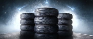 Three stacks of car tires on an asphalt road.